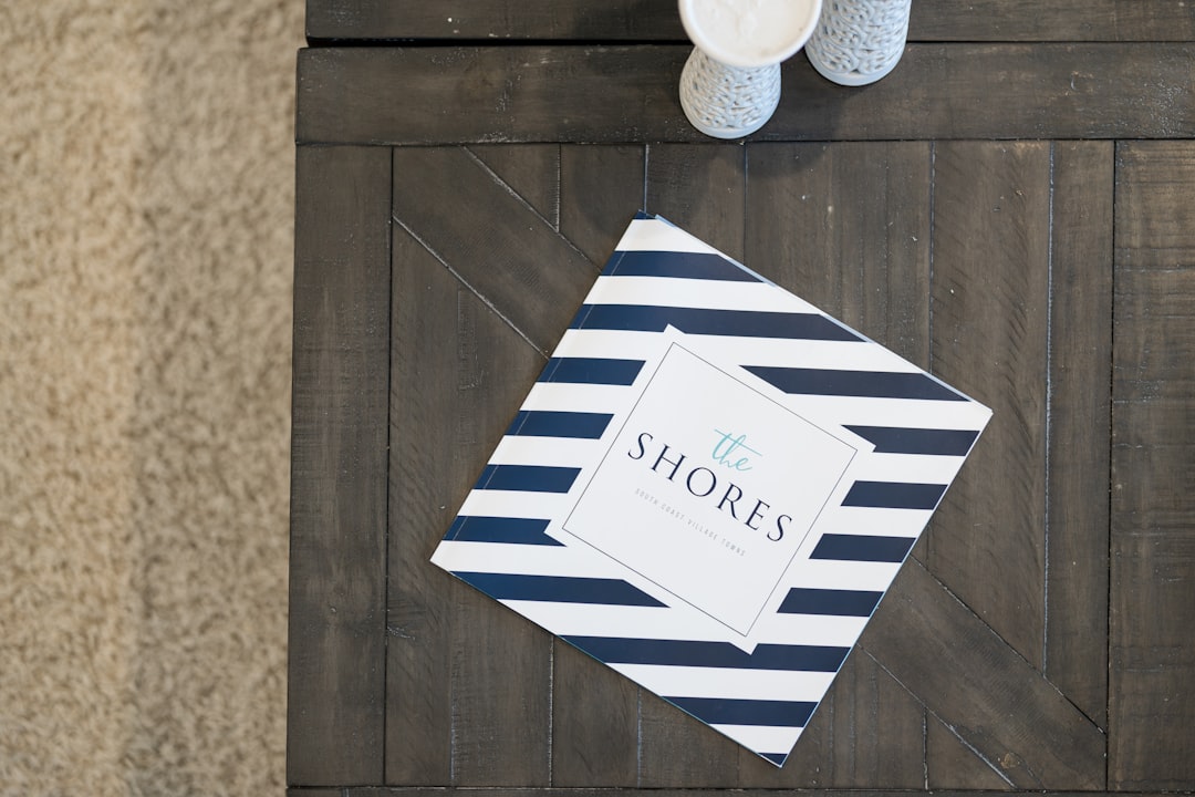 a-book-with-blue-and-white-stripes-titled-the-shores-uswtdyyakd0